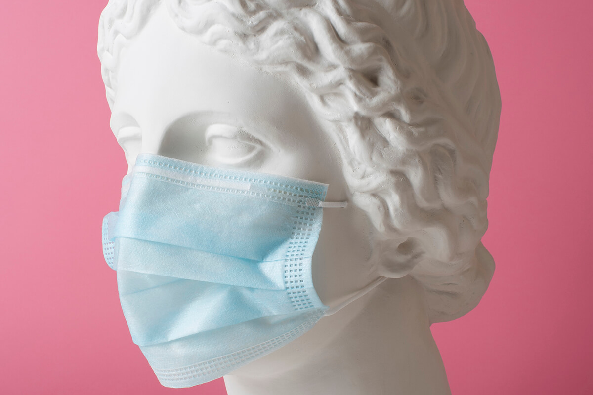 marble sculpture of a historical figure wearing a blue medical mask. Image by freepik